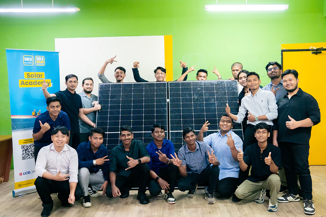 SOLS Solar Academy 学员与太阳能电池板在 Solar Academy 横幅旁合影